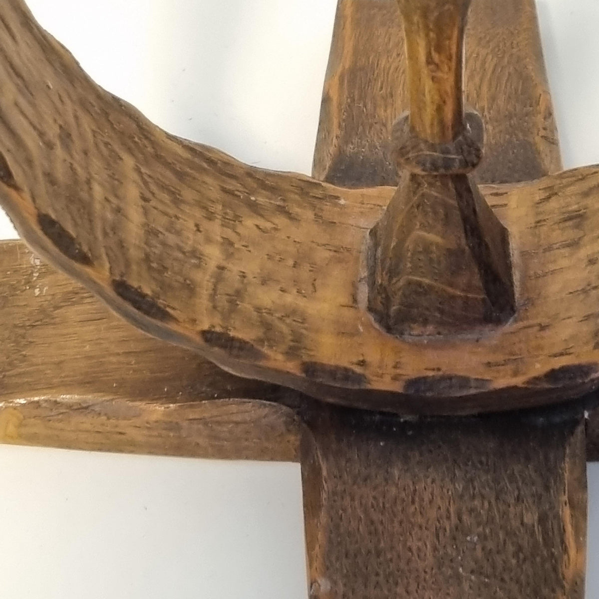 a close-up view of a wooden object, possibly a piece of furniture or a tool, with a textured and weathered appearance.