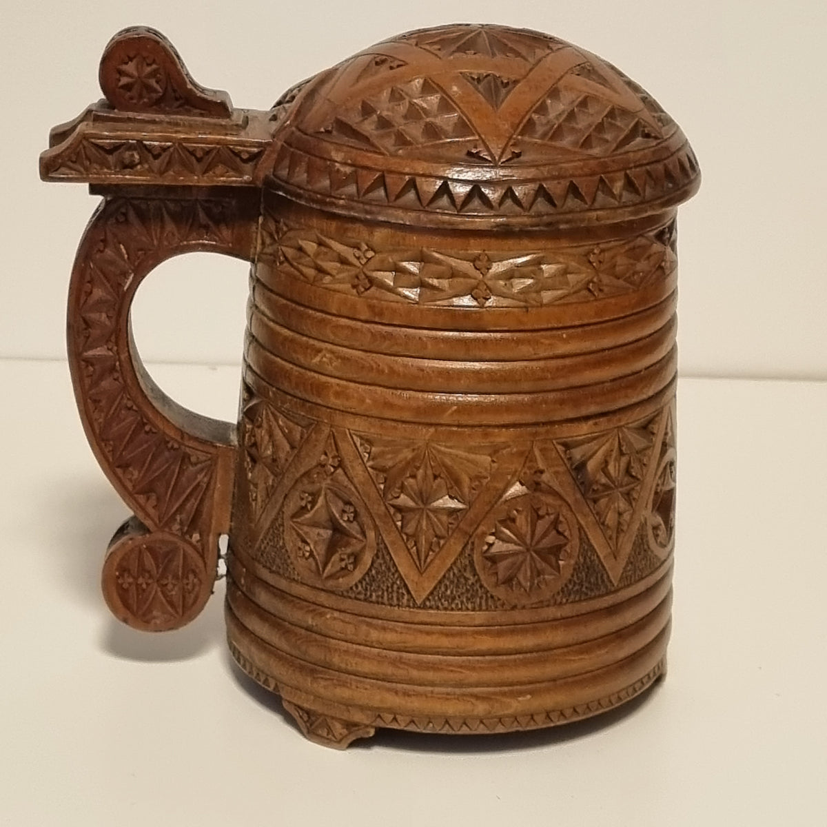 Side view of chip carved wooden tankard with scroll handle and thumb piece