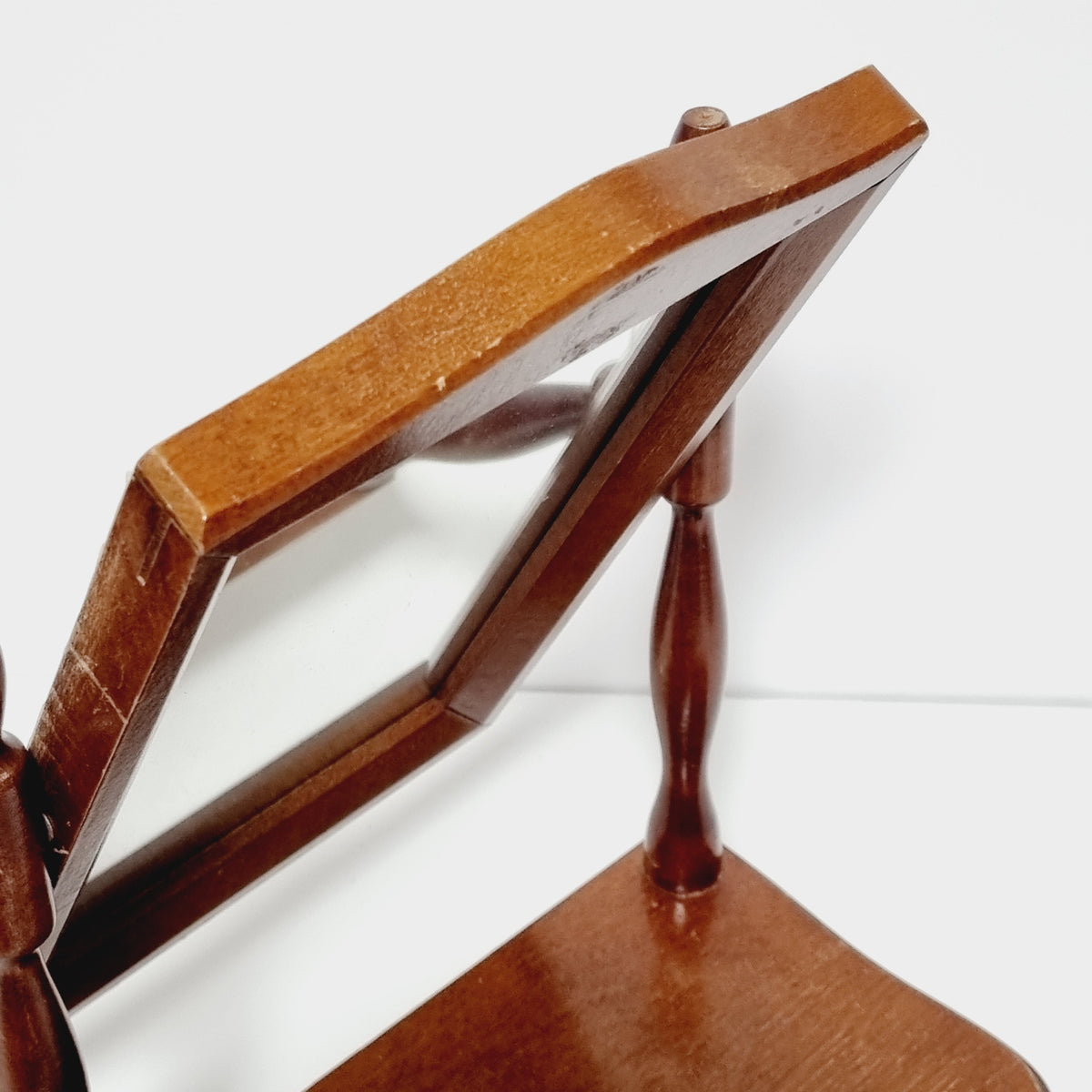 a wooden chair with a mirror attached to it, positioned against a white background.