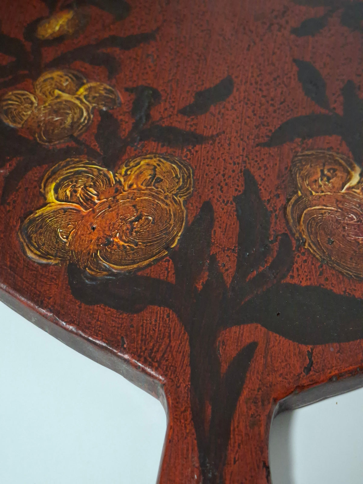 Close-up of raised golden ochre flowers painted on the Swedish folk art bread board