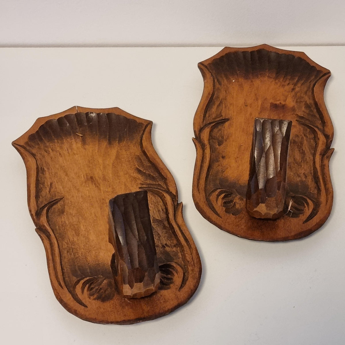 two wooden wall hangings or wall-mounted objects, each with a carved design and a carved piece of wood attached to them.