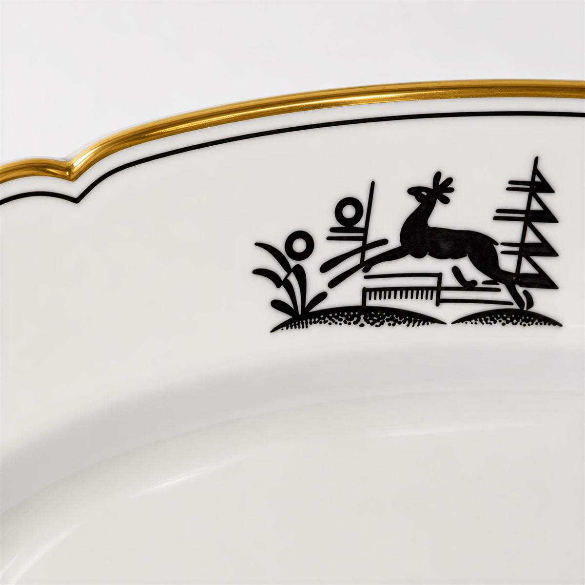 a decorative plate with a black silhouette of a deer and some plants.