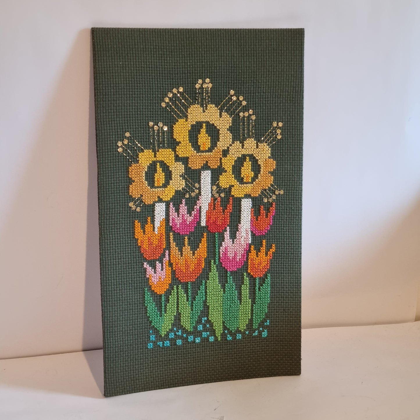 Close-up detail of cross-stitch sunflowers with silver sequins and metallic thread stamens