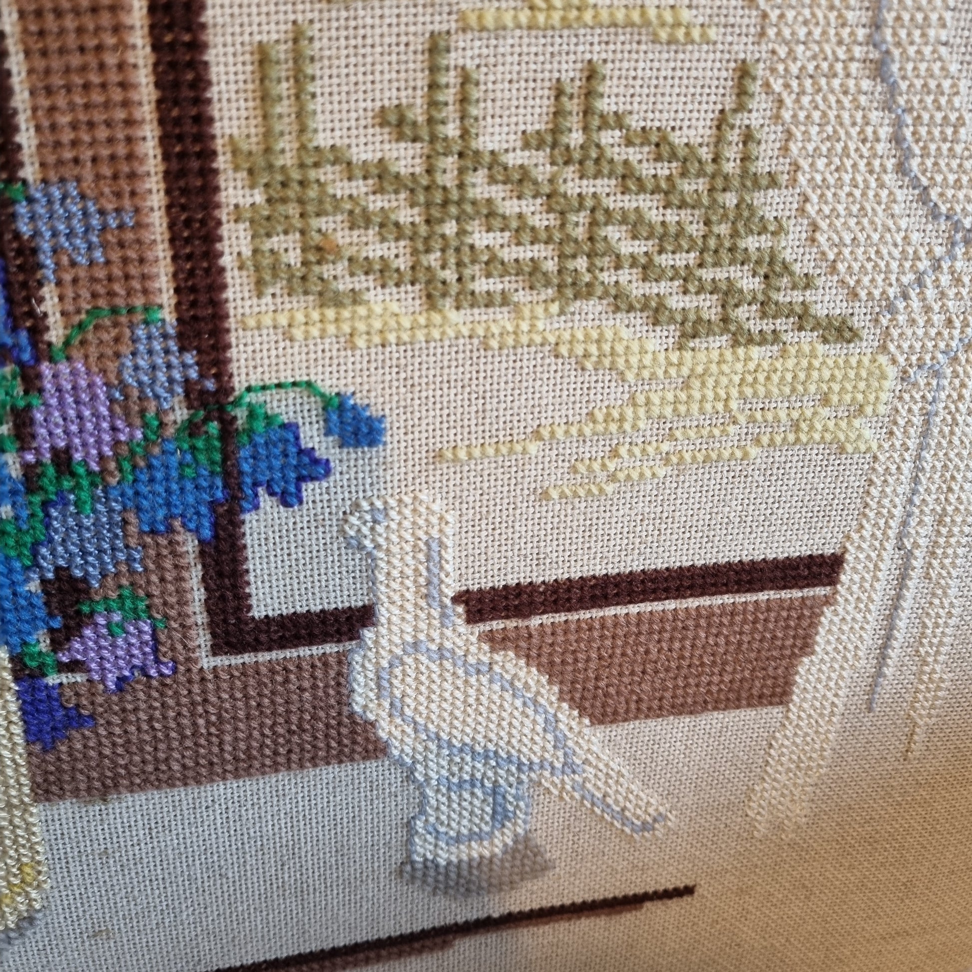 Close-up detail of blue harebells and lilac flowers in yellow vase on wooden windowsill