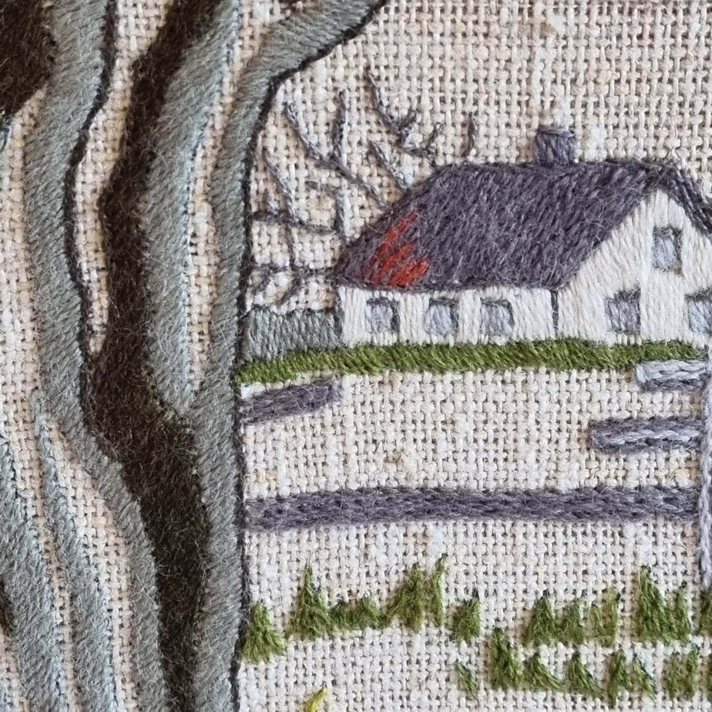 Close-up detail of bare oak tree trunk in grey satin stitch with bird nest in upper branches
