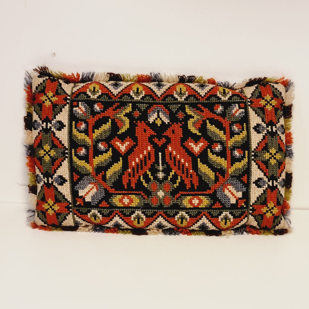 Small vintage embroidered pillow with two facing red birds, floral motifs and multicolored fringe