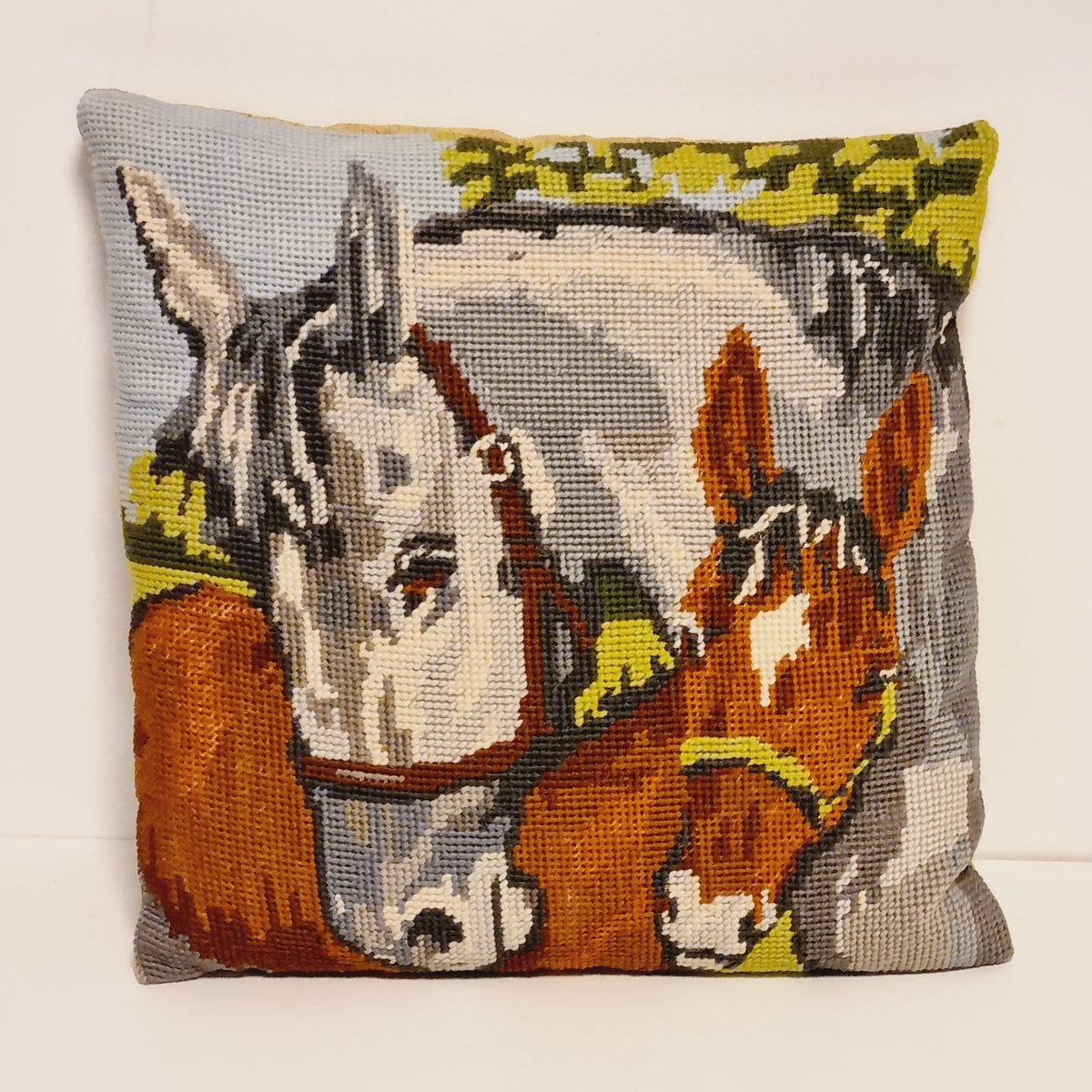 Miniature vintage needlepoint pillow showing a gray horse and a chestnut horse, measuring 20 by 20 cm