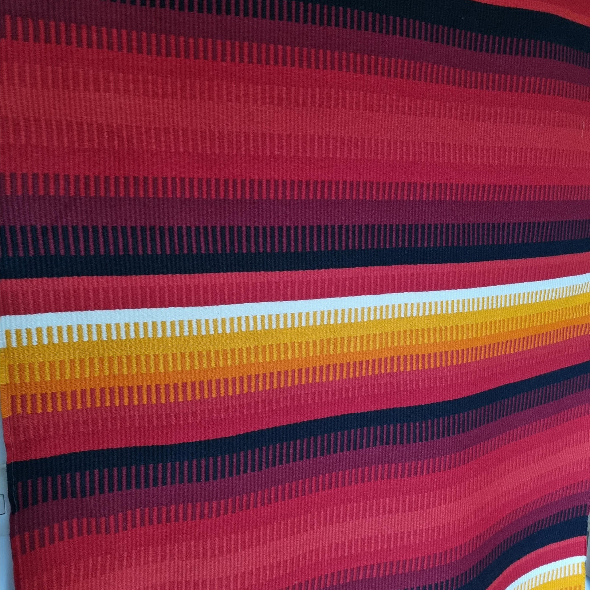 a close-up view of a vibrant, colorful textile with vertical stripes in shades of red, orange, and yellow.