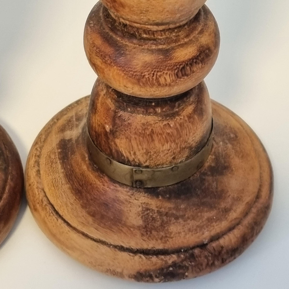 A close-up view of a wooden, weathered piece of furniture, possibly a table or cabinet, with a metal bracket or fastener attached to it.