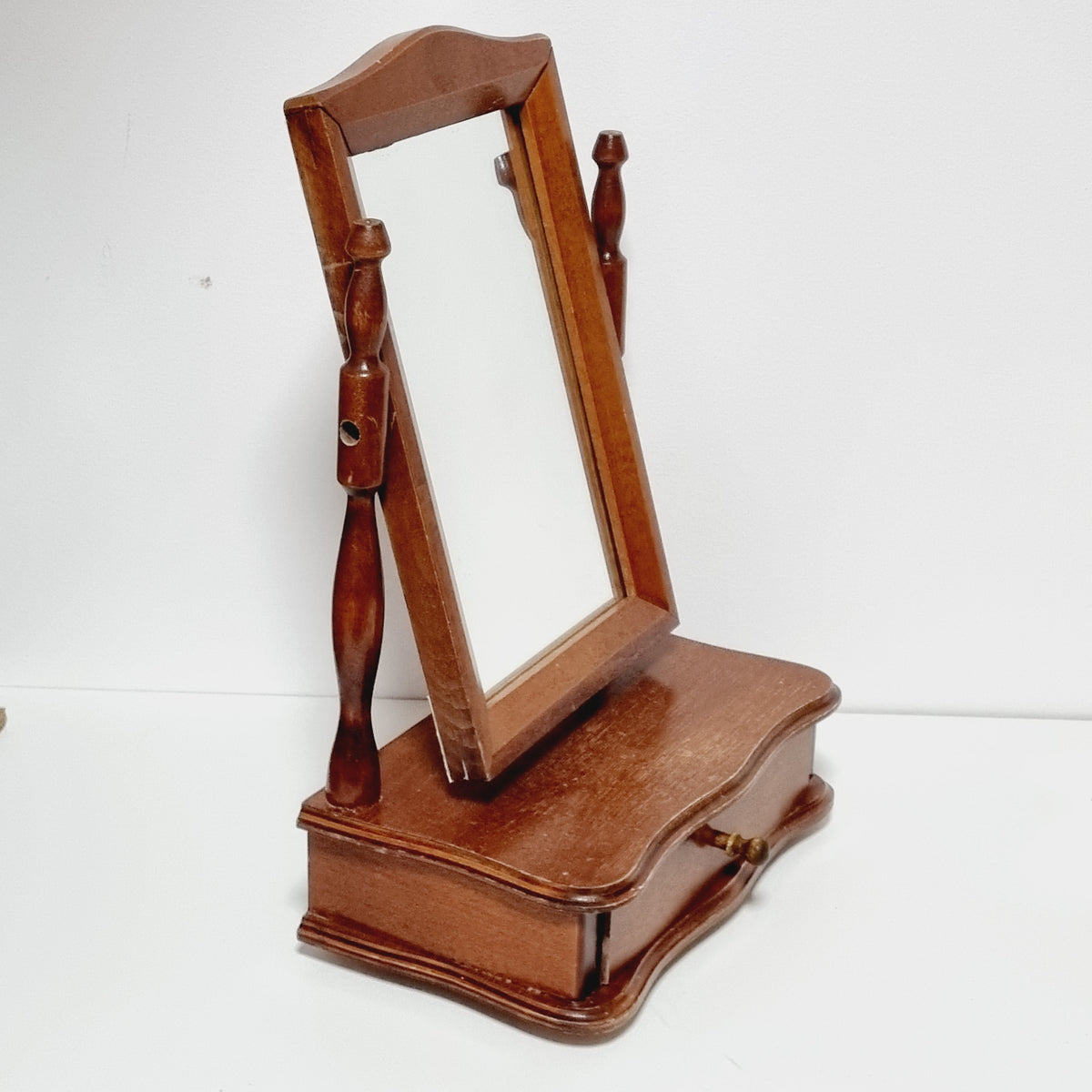 a wooden mirror with a wooden frame, mounted on a wall.
