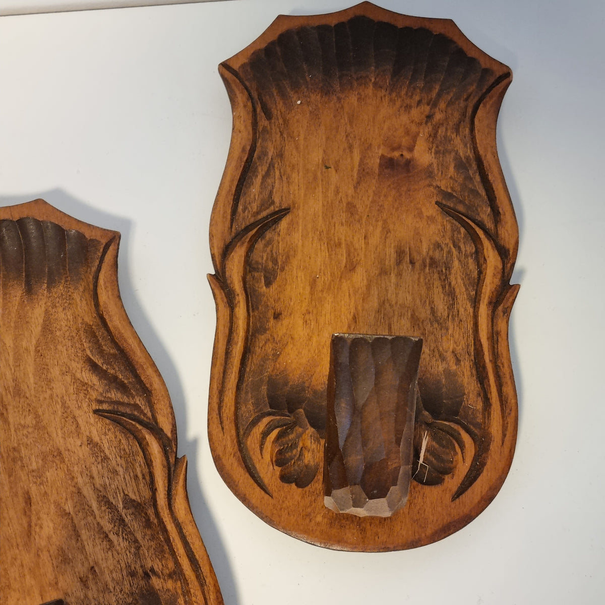 a pair of wooden plaques or stands, each with a carved design on the surface. The plaques appear to be made of wood and are displayed against a white background.