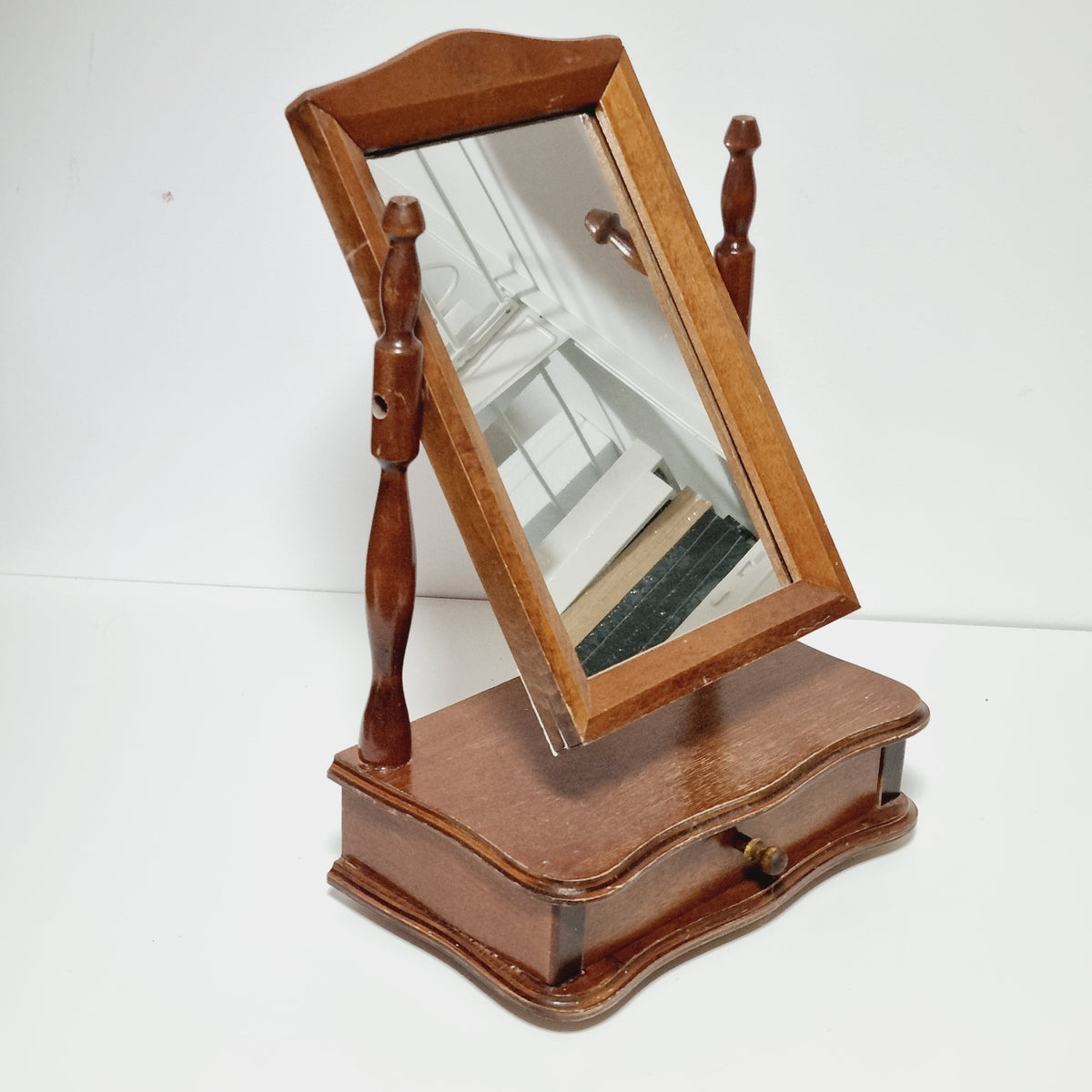 a wooden mirror frame with a wooden handle, mounted on a white wall.
