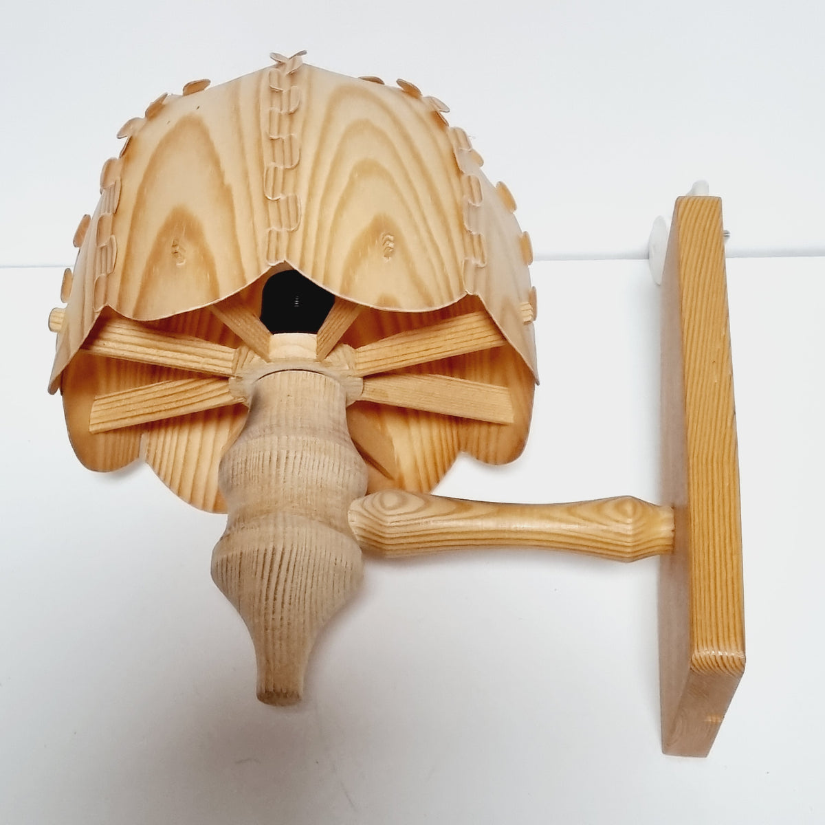 A wooden lamp with a wooden base and a wooden shade, mounted on a wall.