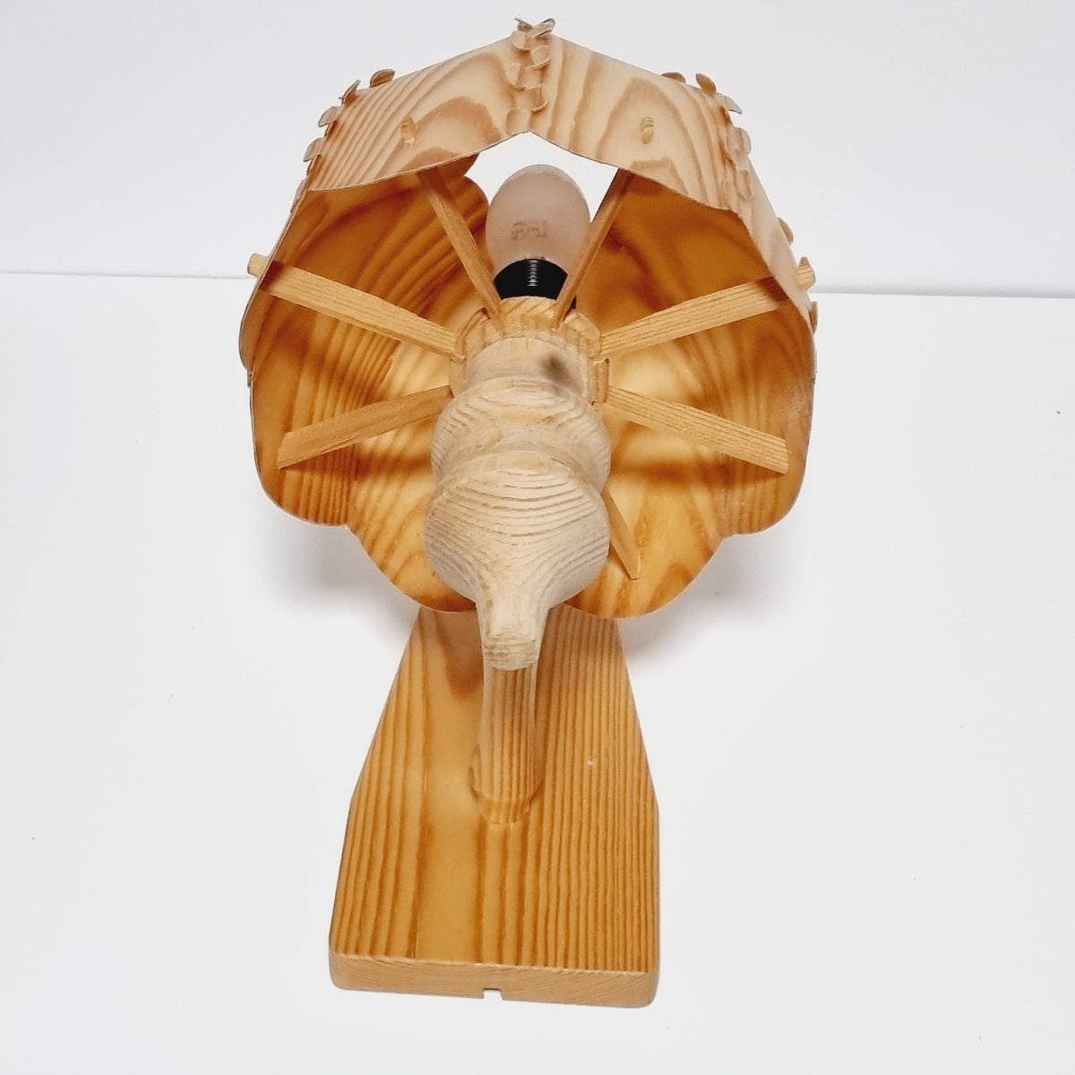 A wooden lamp with a wooden stem and a wooden shade, mounted on a wall.