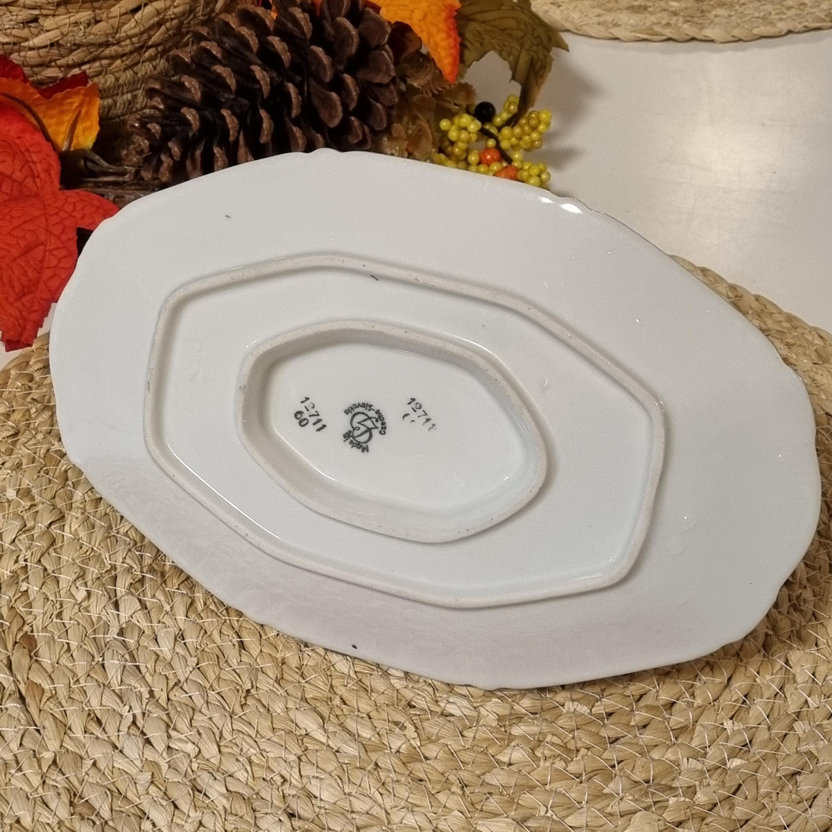 a white ceramic plate with a black logo on it, placed on a woven mat.