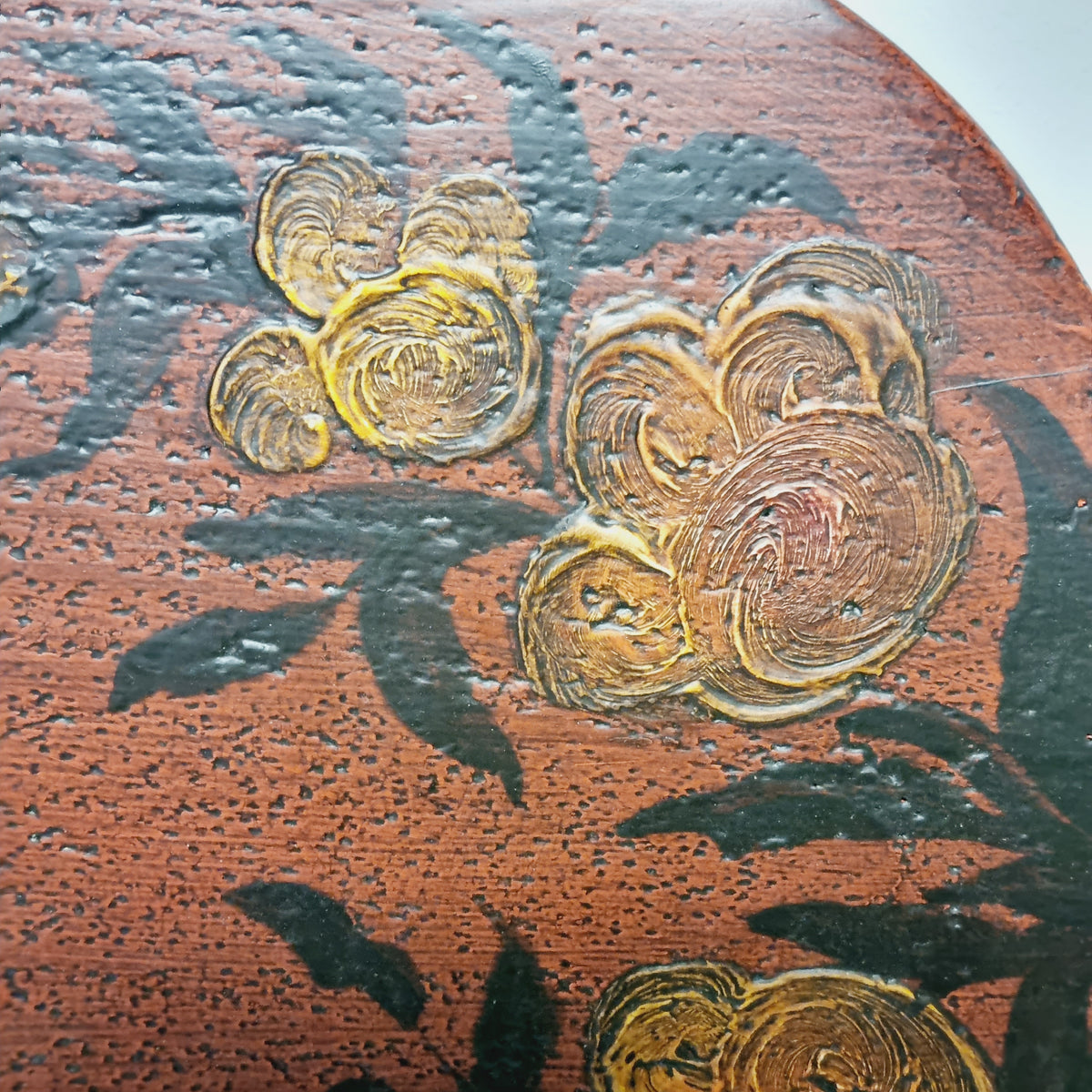 Close-up of stylized flowers and dark leaves on the Falu red bread board