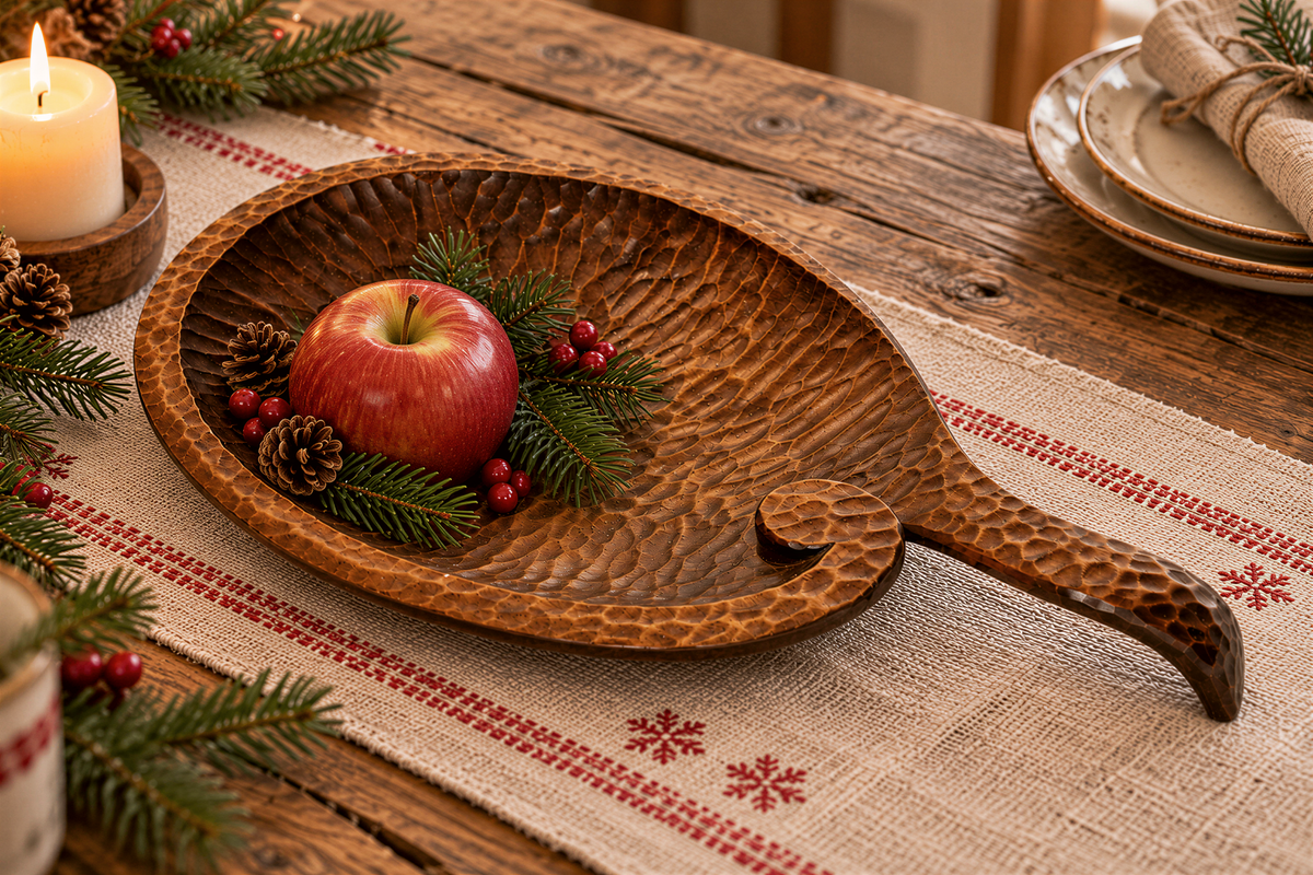 Hand carved wooden leaf dish holding a red apple and pine branches