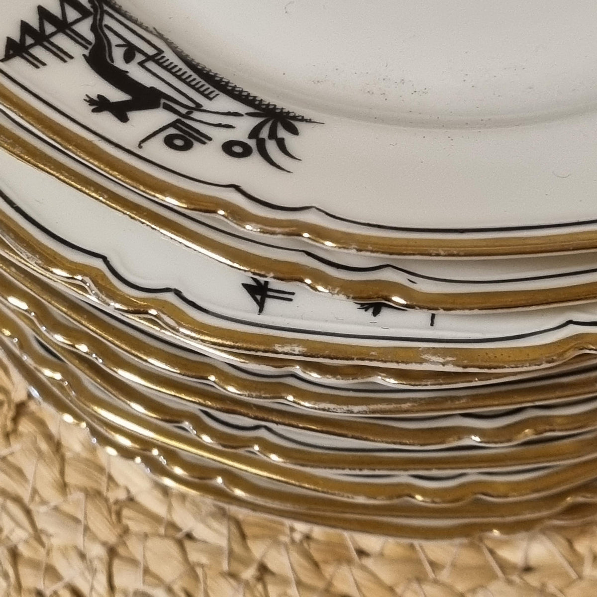 A close-up view of a stack of ornate plates with gold trim, featuring intricate black and white designs.