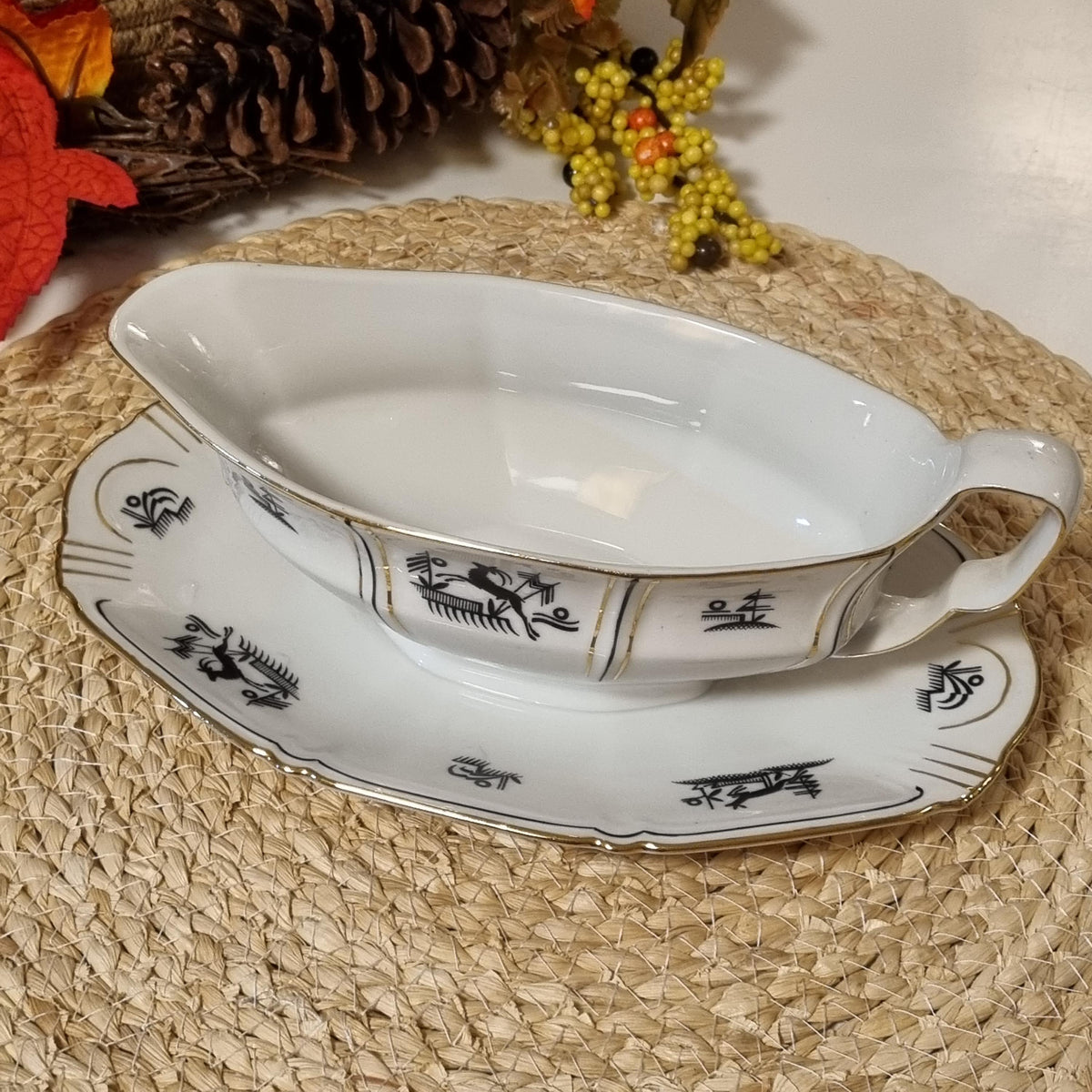 a white ceramic bowl with black designs on it, placed on a woven placemat.
