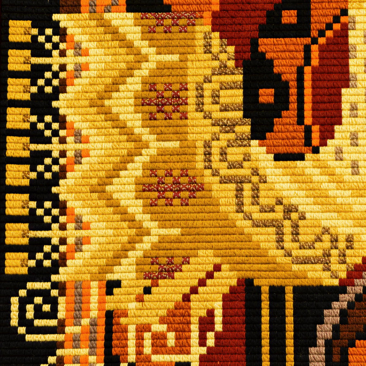 The image is a close-up of a colorful, intricate textile or fabric with a repeating pattern of geometric shapes and designs in shades of yellow, orange, and black.