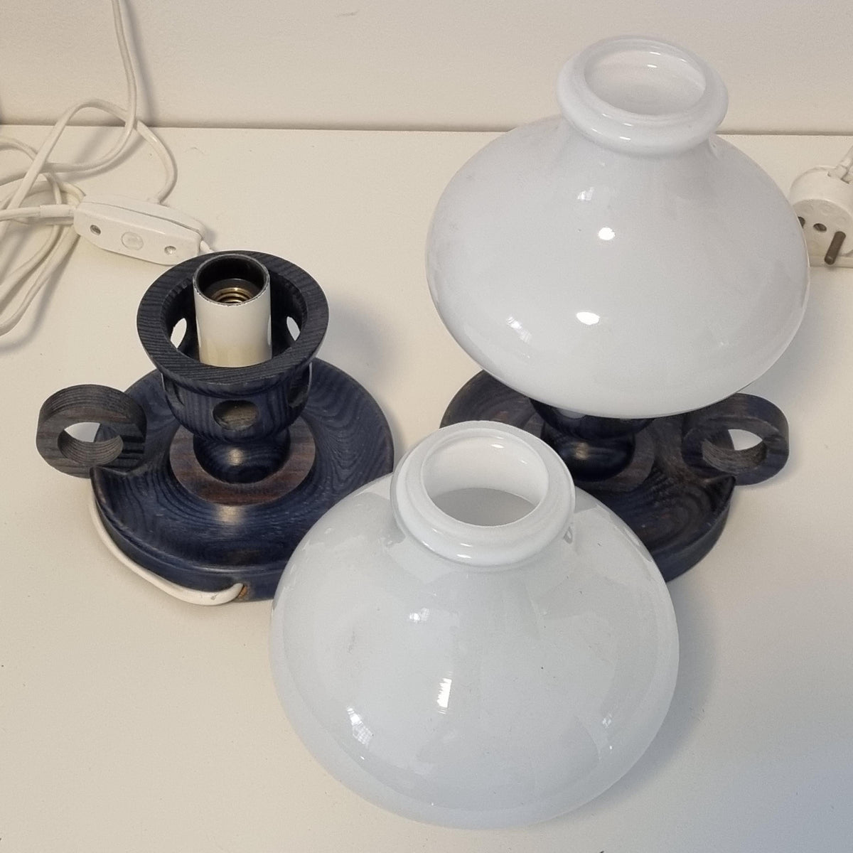 two light fixtures, one white and one blue, sitting on a white surface.