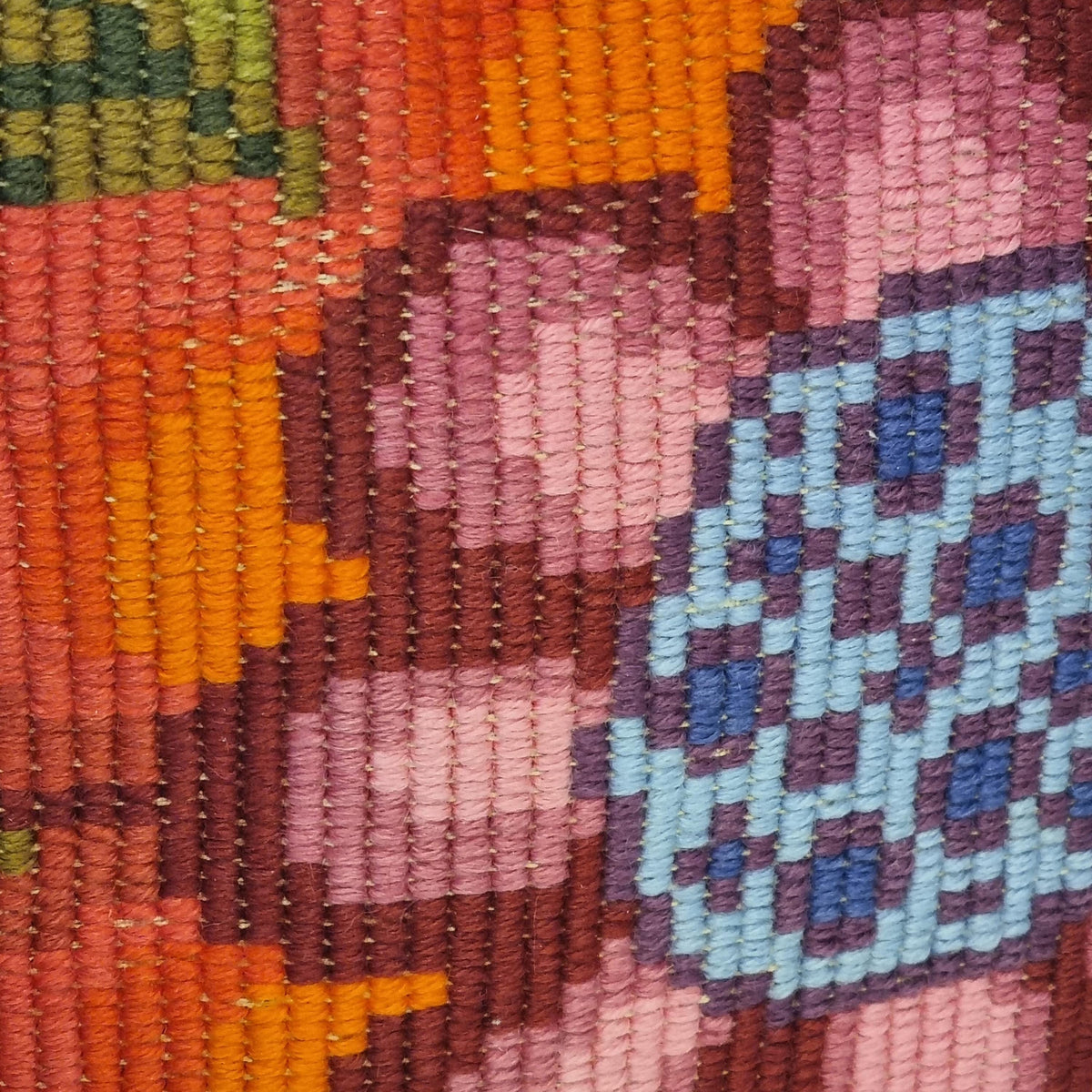The image is a close-up of a colorful, hand-stitched embroidered design featuring a variety of vibrant colors and patterns.