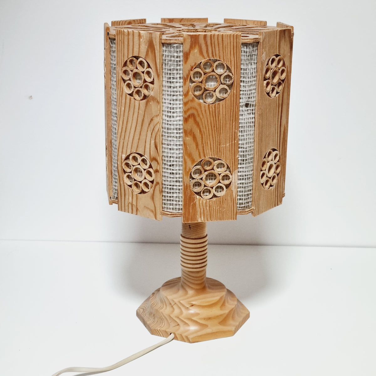 A wooden lamp with a curved, wooden base and a circular pattern on the side.