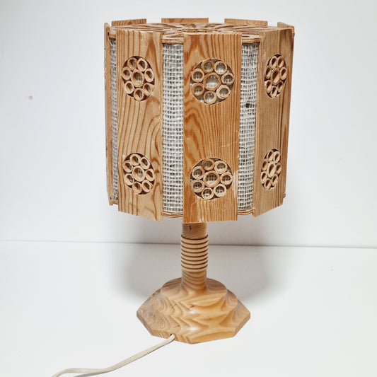 A wooden lamp with a curved, wooden base and a circular pattern on the side.