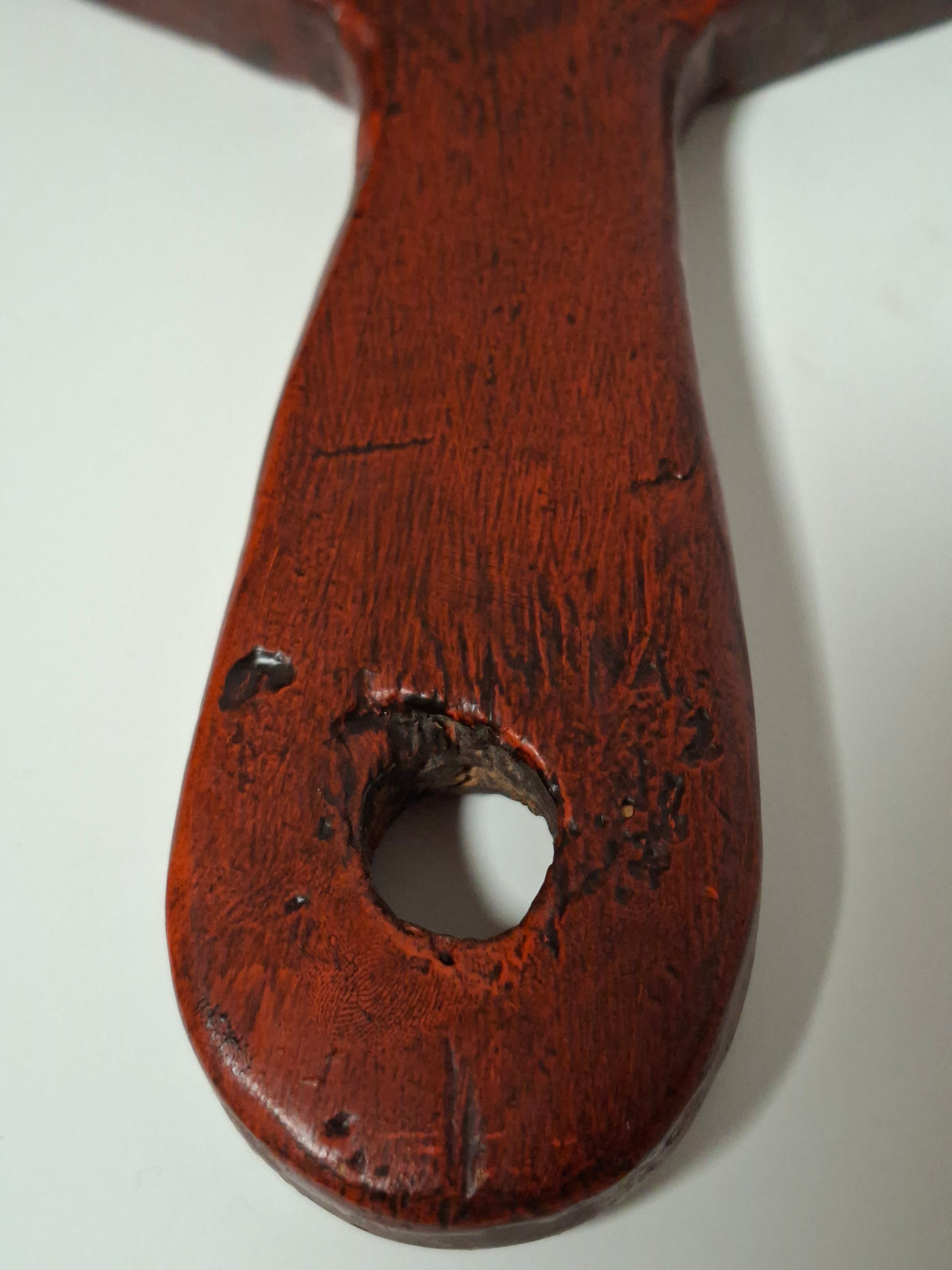Worn hanging hole and handle of the antique painted bread board