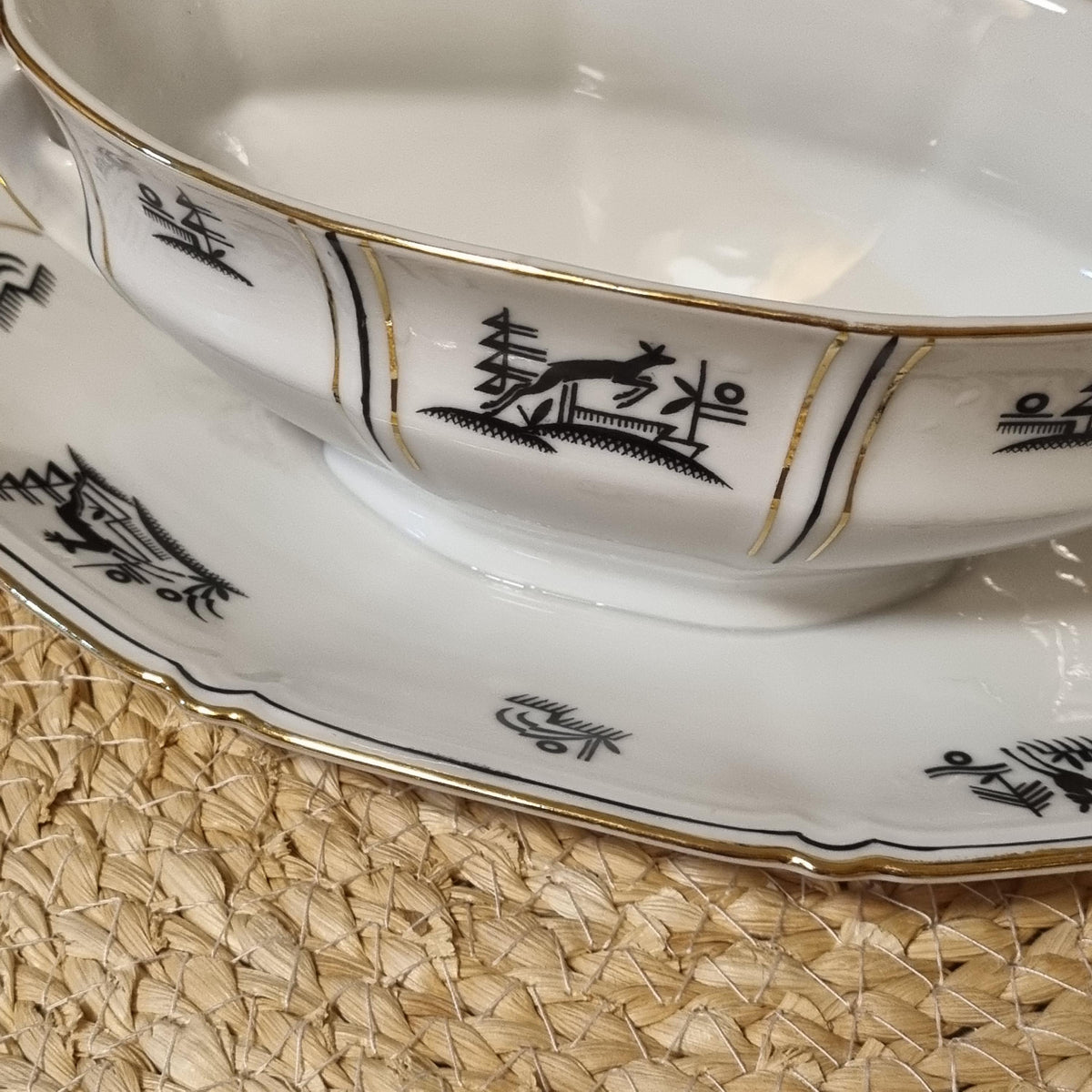 a close-up view of a white porcelain bowl with gold trim and black Chinese characters on it, placed on a woven placemat.