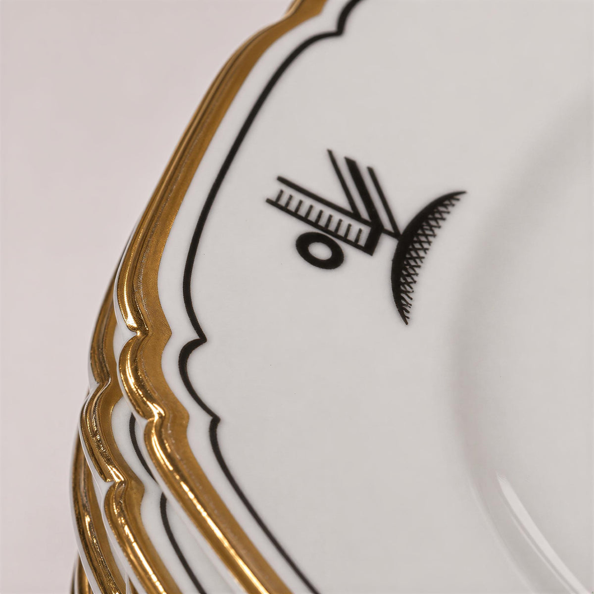 A close-up image of a white plate with a gold border, featuring a black and white design on the plate.