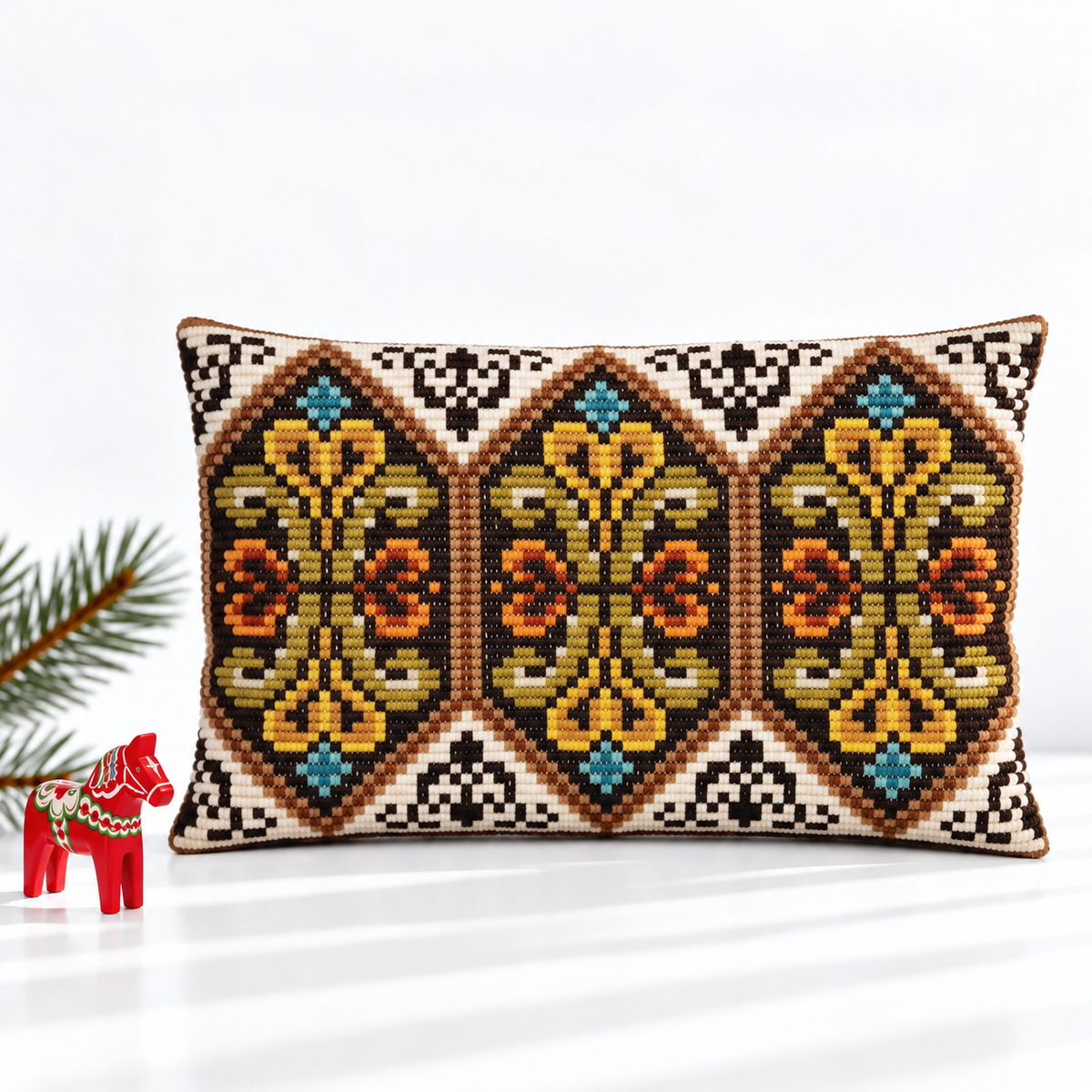Mustard and turquoise floral embroidered pillow styled with a red Dala horse and evergreen branch
