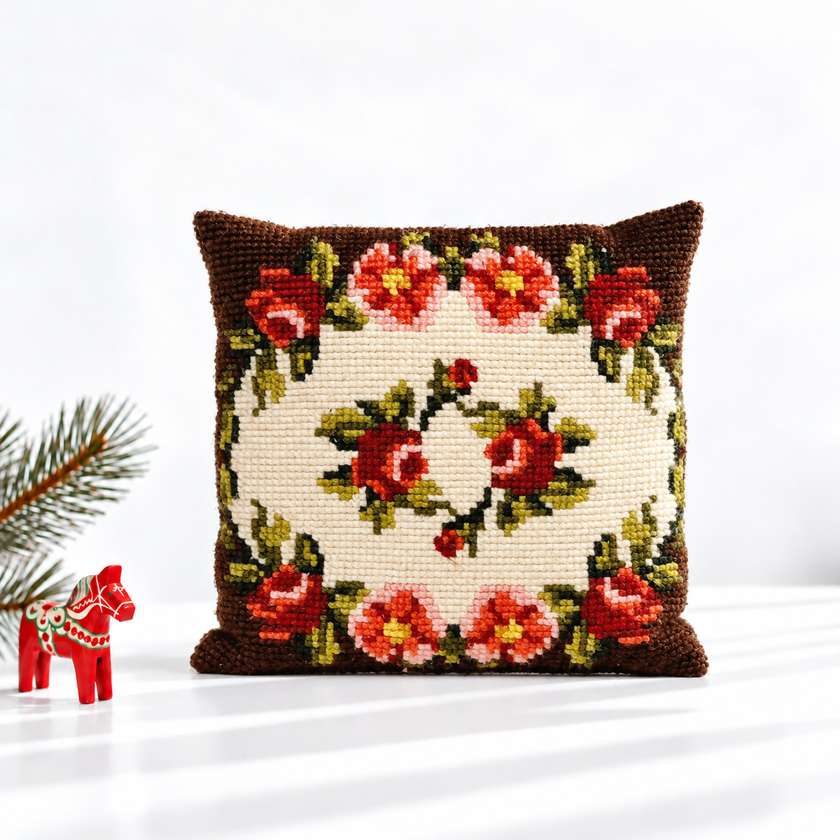 Rose needlepoint pillow styled with a red Dala horse and evergreen branch