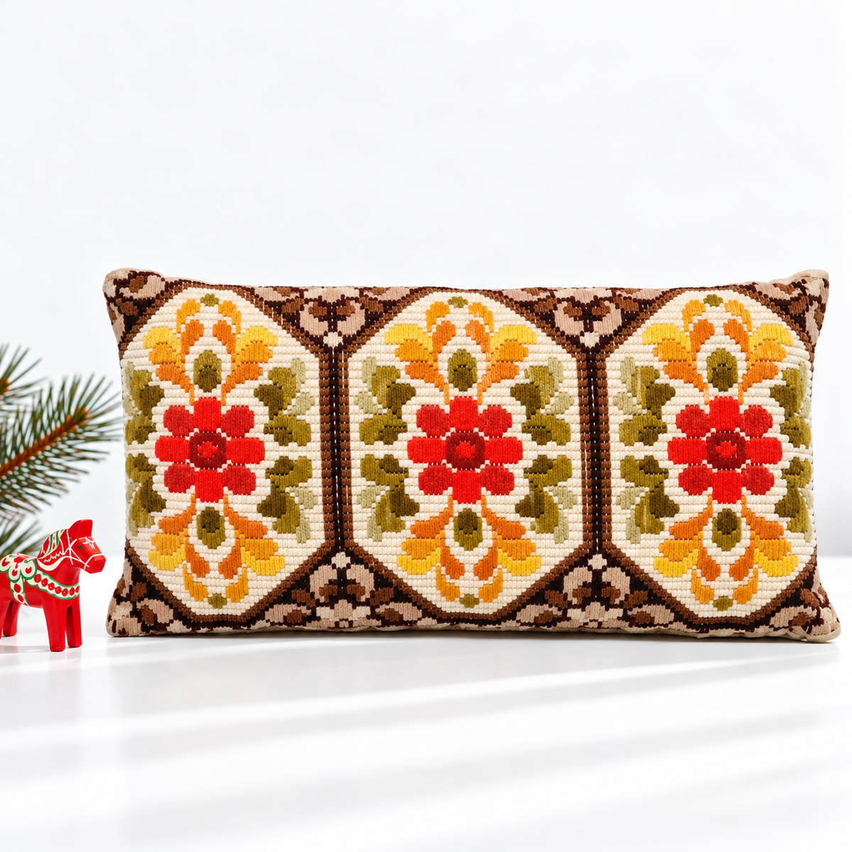 Floral embroidered lumbar pillow styled with a red Dala horse and evergreen branch