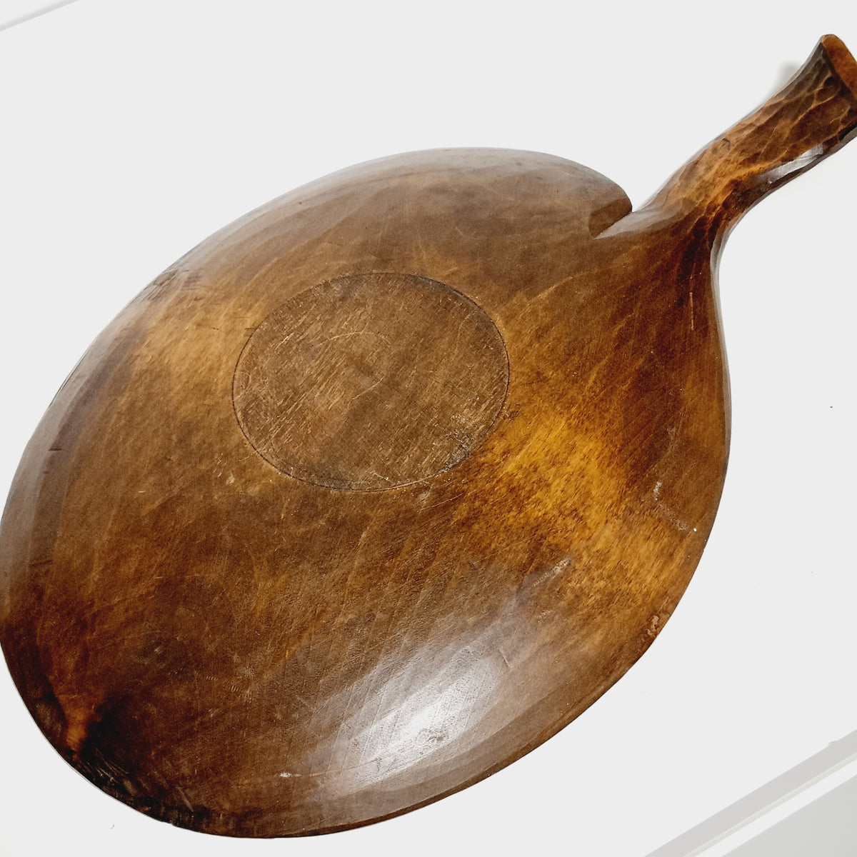 Smooth underside of hand carved wooden dish with circular foot