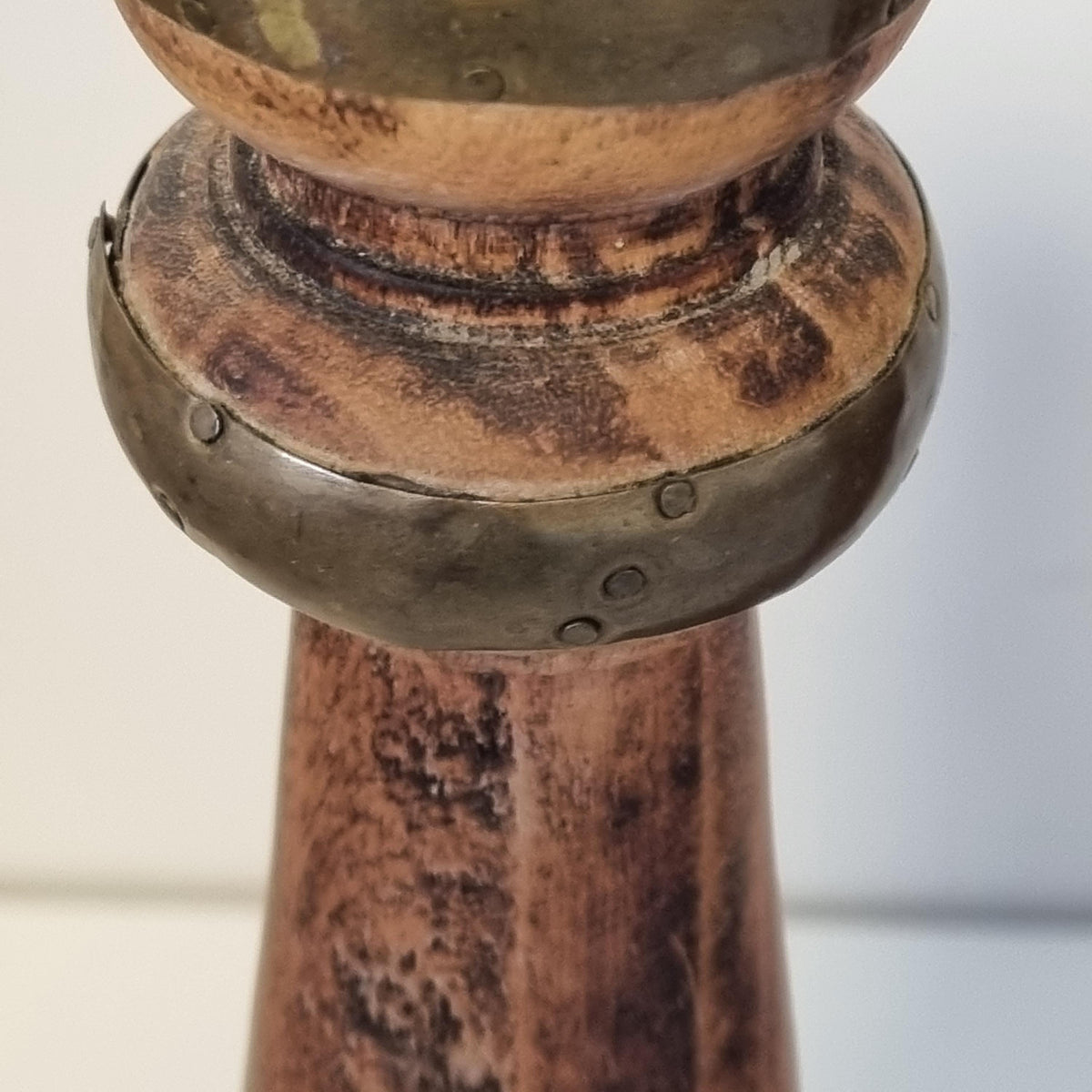 A close-up view of a wooden pole with a metal bracket attached to it, set against a blurred background.
