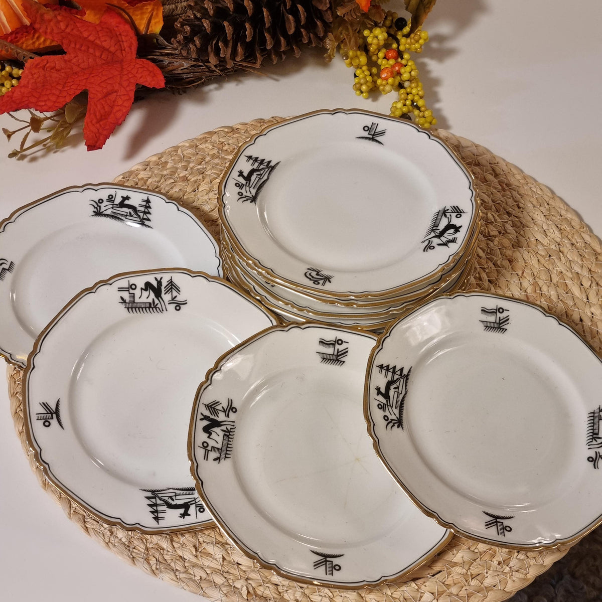 A set of white plates with black designs, arranged on a woven placemat.