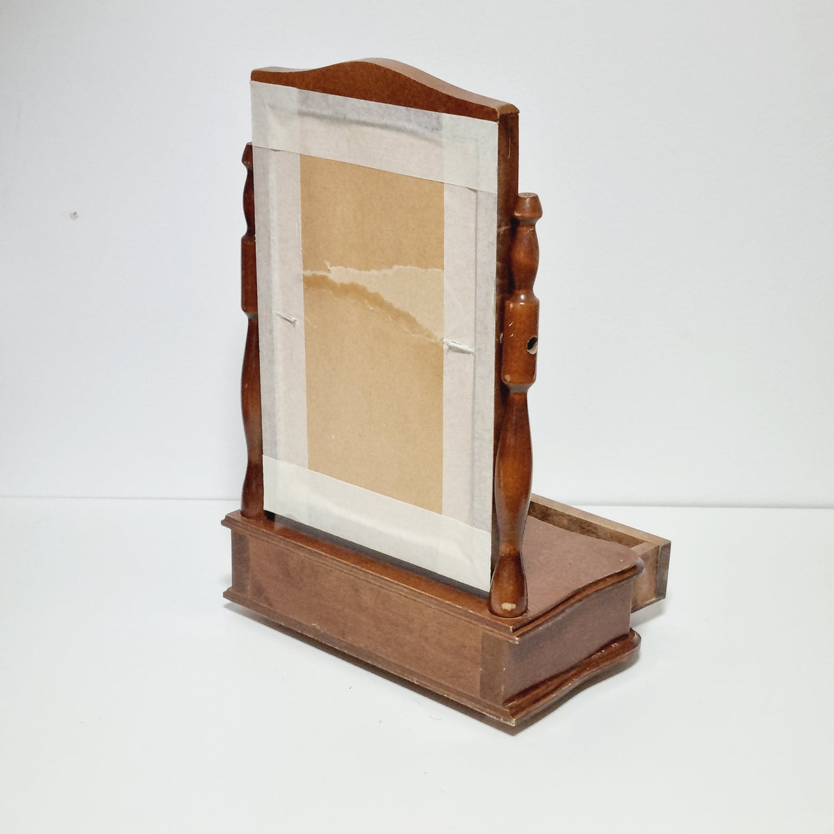 a wooden shelf or cabinet mounted on a wall, with a piece of paper taped to it.