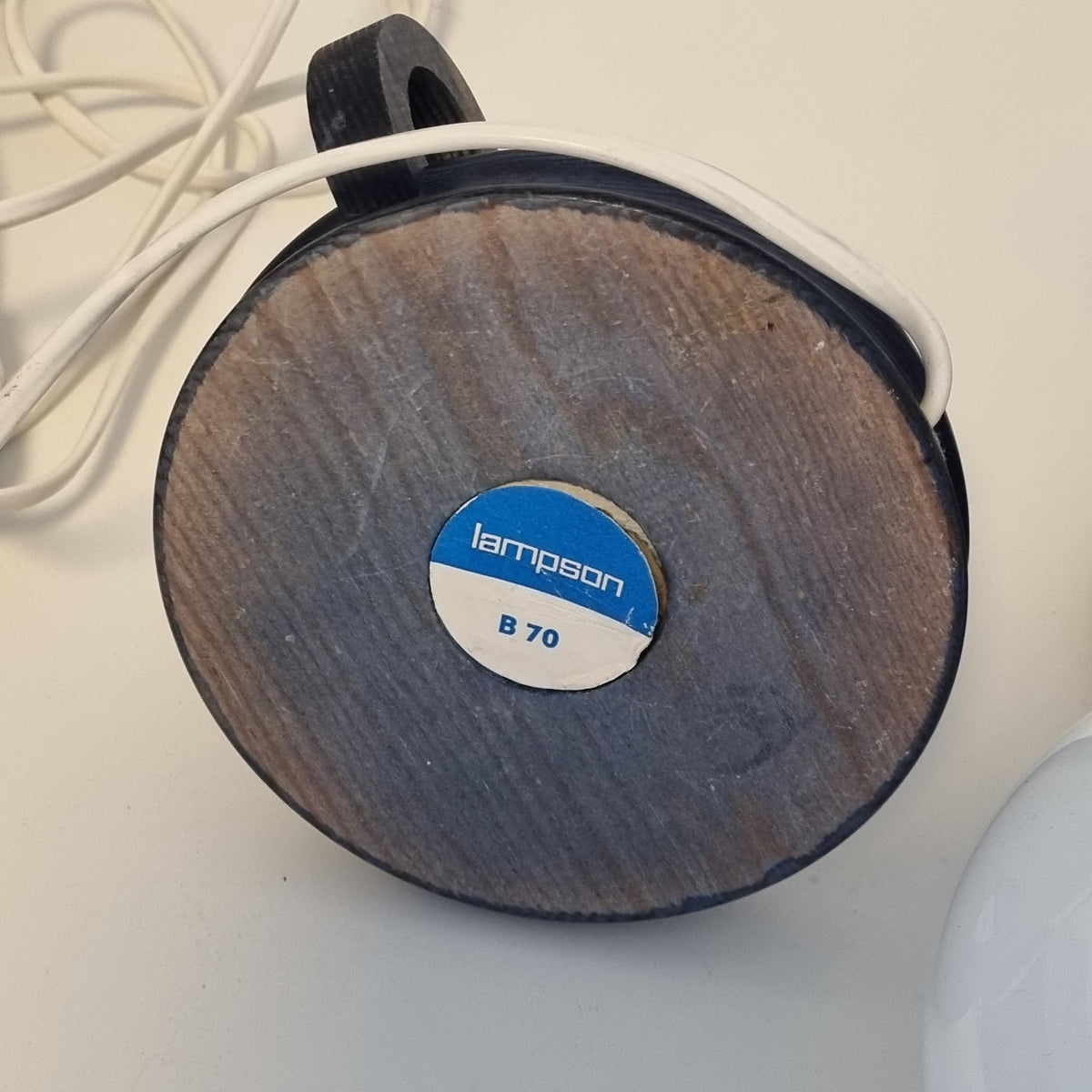 a wooden base with a blue and white sticker on it, placed on a white surface.
