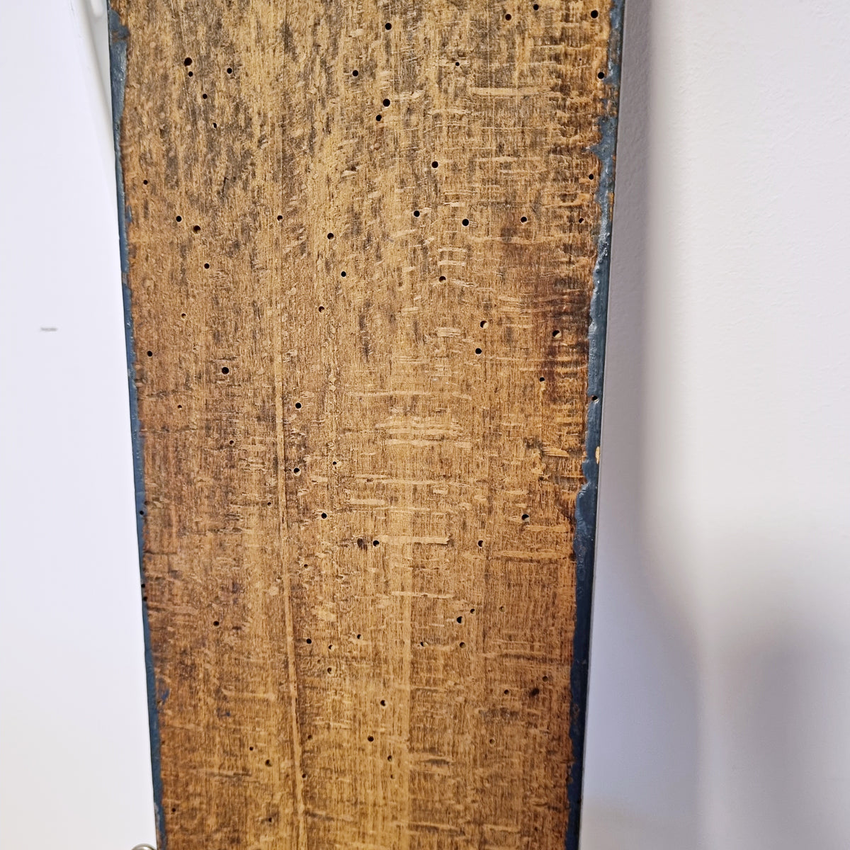 Back of antique Swedish wall hook showing hand-worked wood and old woodworm holes
