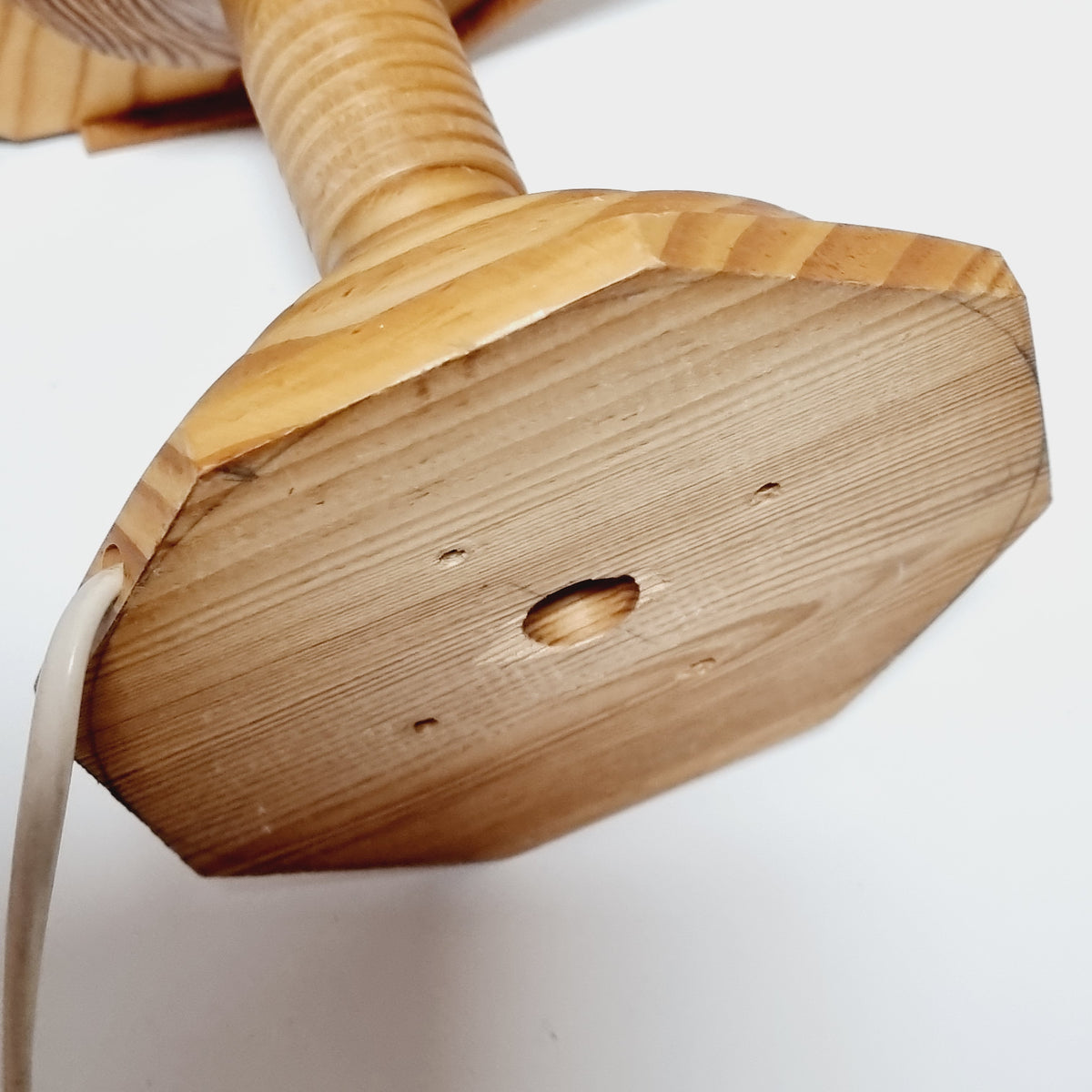 a close-up view of a wooden object, possibly a piece of furniture or a decorative item, with a hole in the center.
