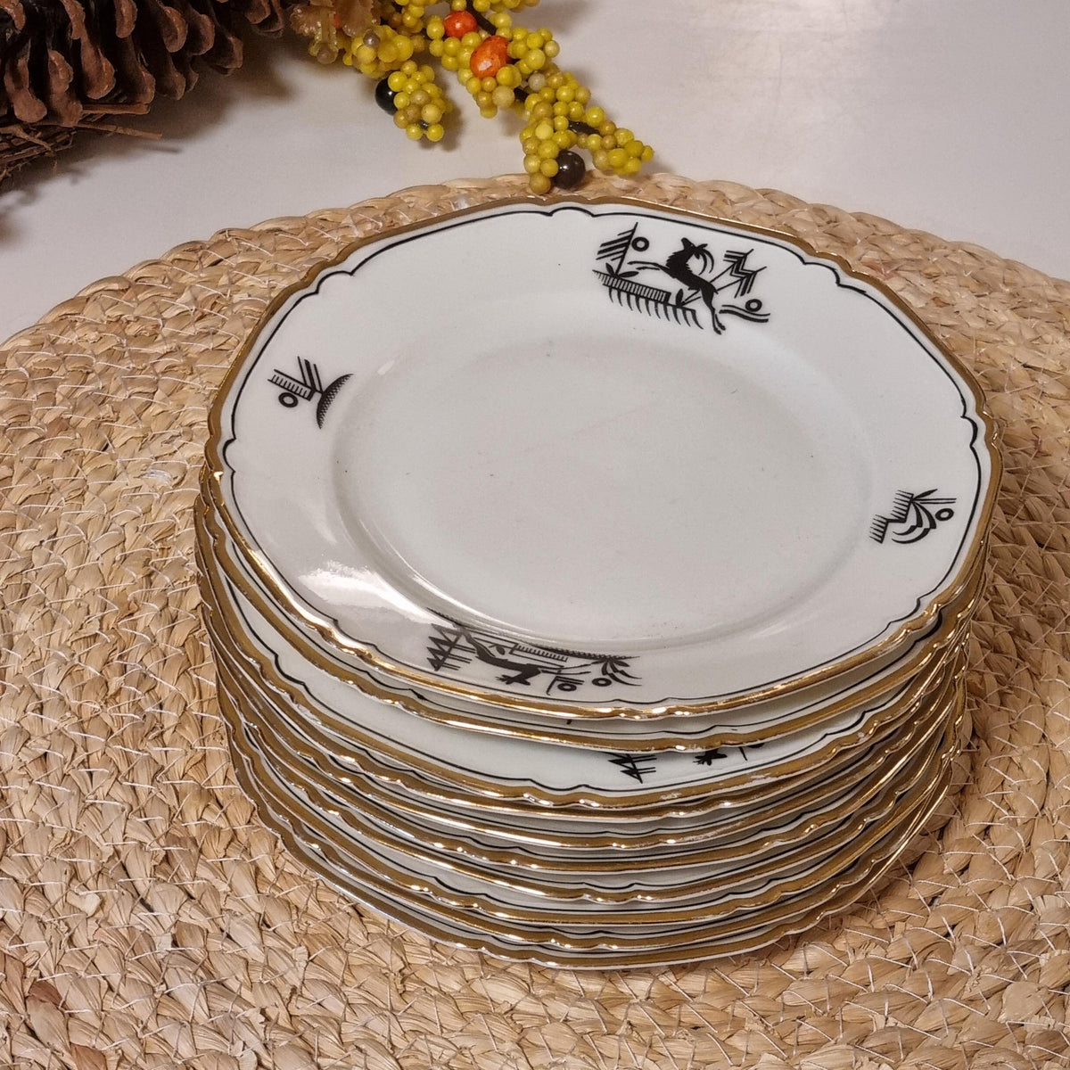 A stack of ornate white plates with gold trim, arranged on a woven placemat.
