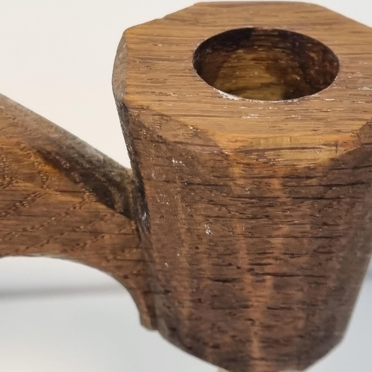 A close-up view of a wooden object, possibly a piece of furniture or a tool, with a hole in the center. The object appears to be made of wood and has a textured, weathered appearance.
