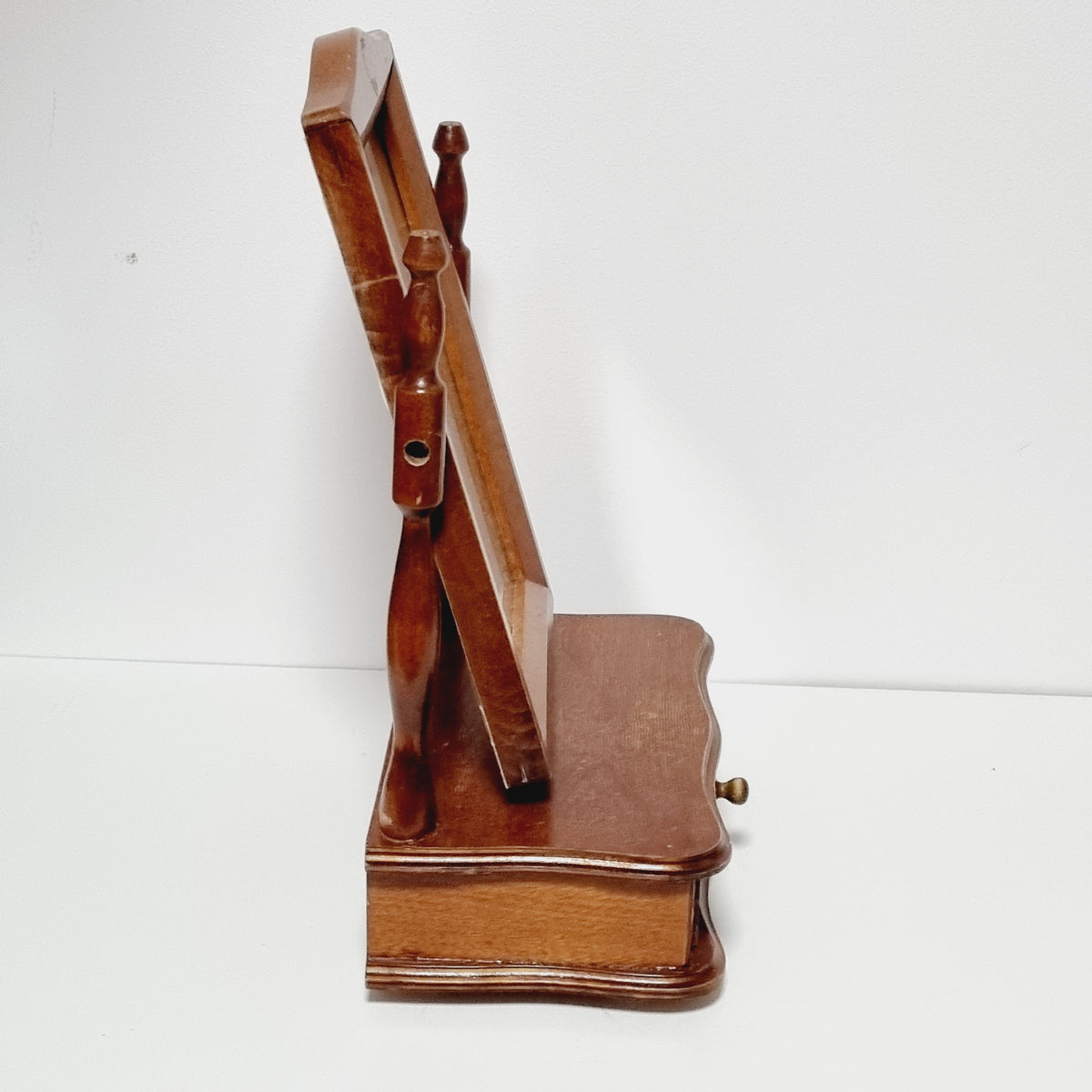 A wooden shelf mounted on a wall, with a wooden handle and a wooden panel on the back.
