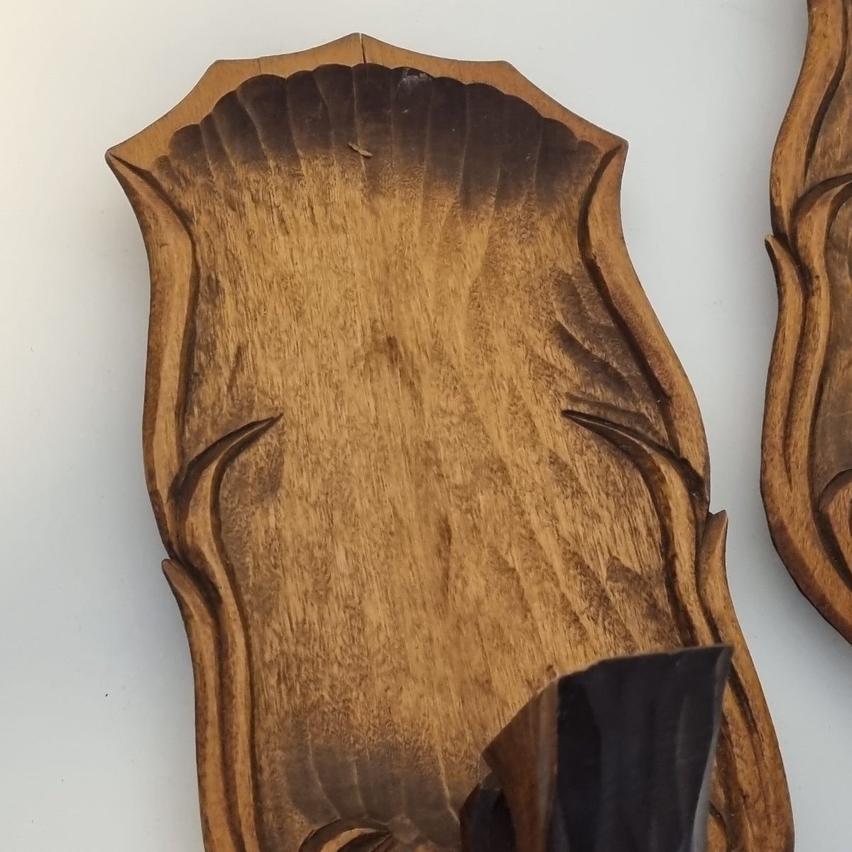 a wooden plaque or board with a carved design, featuring a dark brown color and a textured surface.