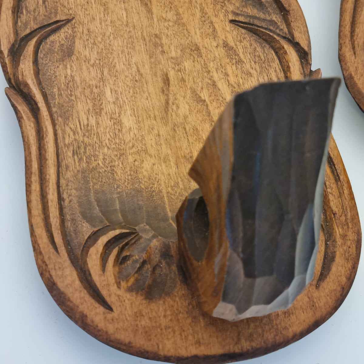 a wooden object with a carved design, including a large, jagged-edged piece of wood and a smaller, more intricate piece.