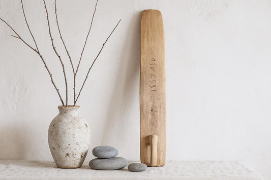 Antique Hand-Carved Butter Paddle 1859: Scandinavian Folk Art Decor displayed with vase and smooth stones on neutral surface