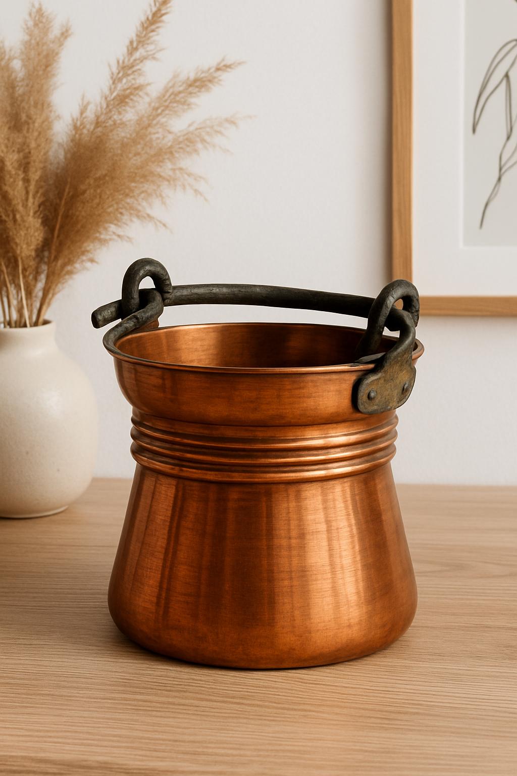 Antique Copper Bucket: Rustic Farmhouse Cauldron with Iron Handle placed on wooden table in cozy decor setting