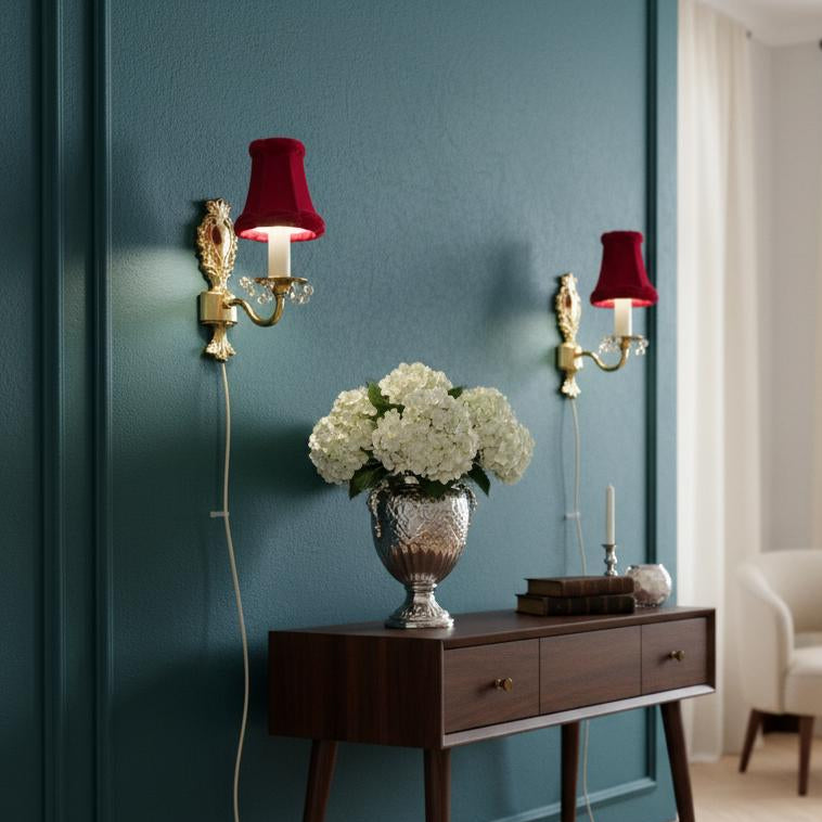 Vintage Rococo style gilded wall lamps pair with original velvet shades mounted above wooden console with flowers and books